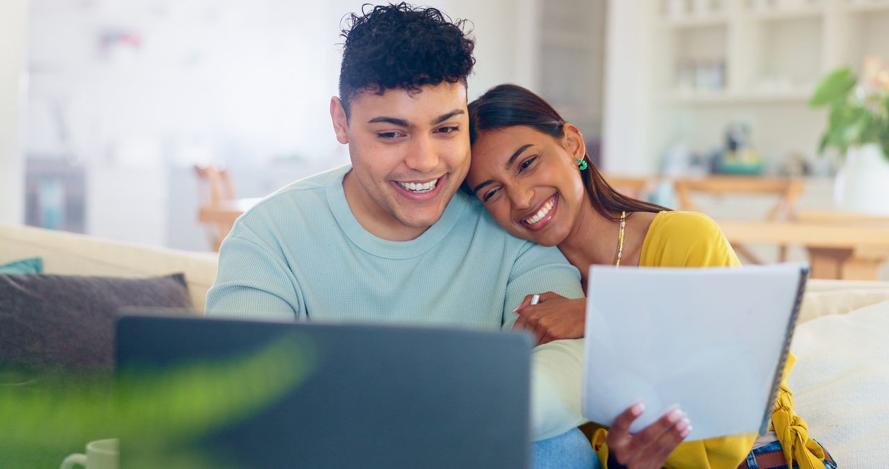 Happy young couple reviewing their finances together on a laptop at home